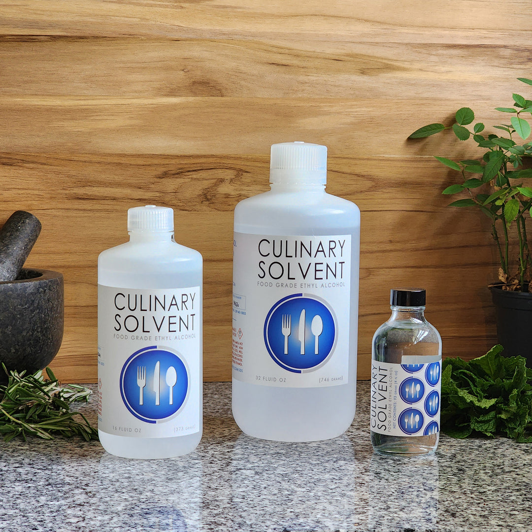 Pure 200 Proof Food Grade Ethanol pint, quart, glass bottle by Culinary Solvent with rosemary, mint, and fresh herbs for tincture on teak wood background