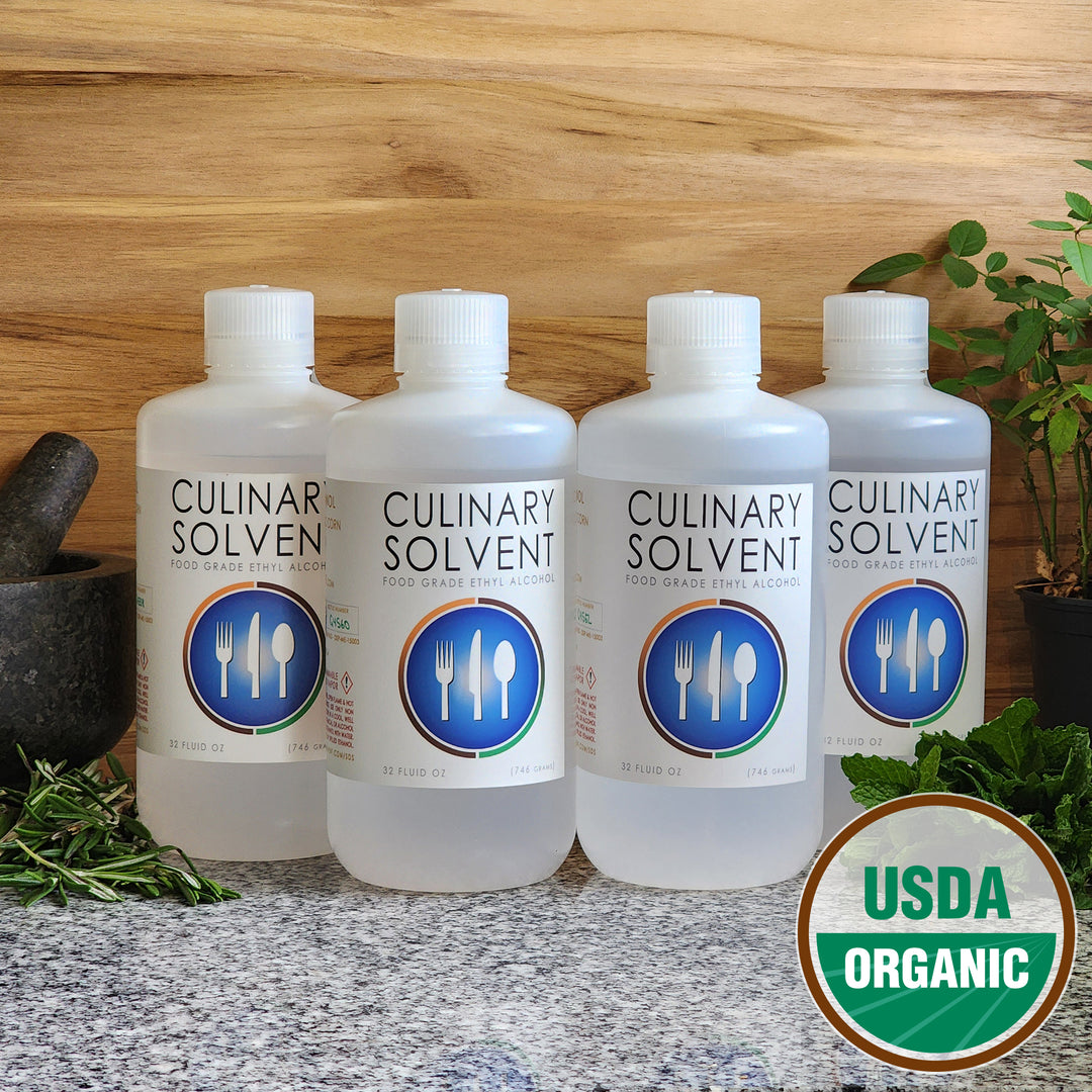 Pure USDA Organic Food Grade Ethanol gallon bottle by Culinary Solvent with rosemary, mint, and fresh herbs for tincture on teak wood background