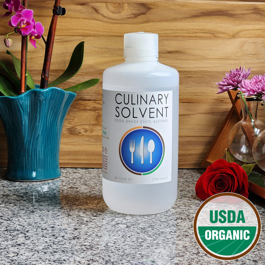 Pure Organic Perfumers Alcohol quart bottle by Culinary Solvent food grade ethanol with orchids, roses, and fresh flowers teak wood background