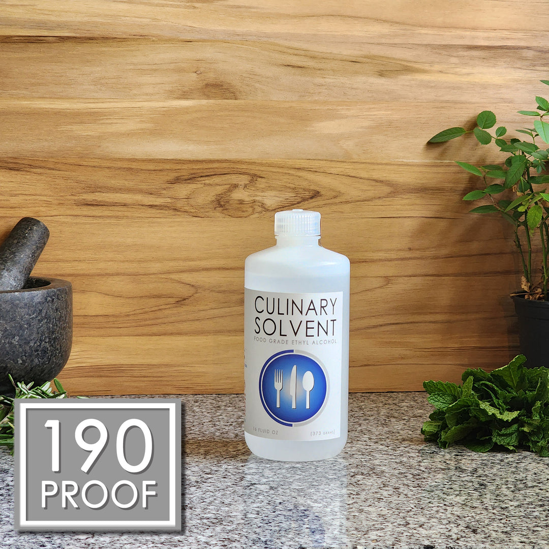 Pure 190 Proof Food Grade Ethanol pint by Culinary Solvent with rosemary, mint, and fresh herbs for tincture on teak wood background
