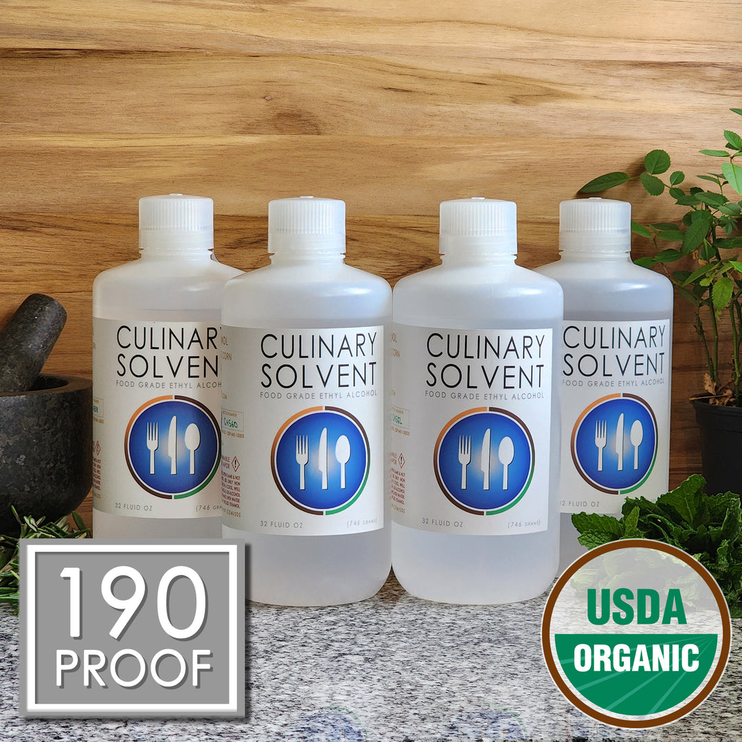 Pure USDA Organic Food Grade Ethanol gallon bottle by Culinary Solvent with rosemary, mint, and fresh herbs for tincture on teak wood background