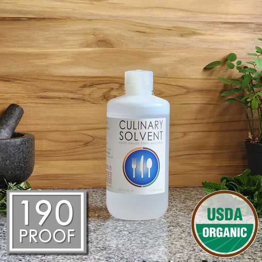 Pure USDA Organic Food Grade Ethanol quart bottle by Culinary Solvent with rosemary, mint, and fresh herbs for tincture on teak wood background