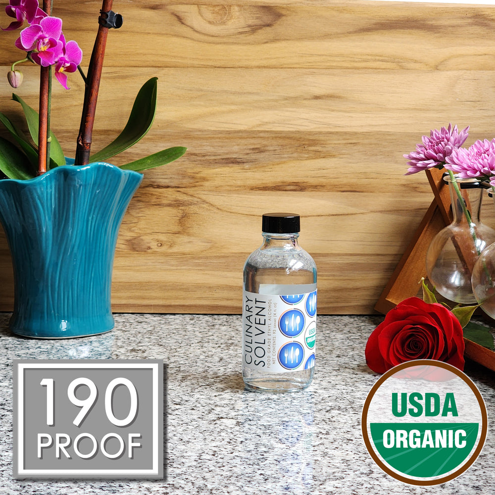 Pure Organic Perfumers Alcohol glass bottles by Culinary Solvent food grade ethanol with orchids, roses, and fresh flowers teak wood background