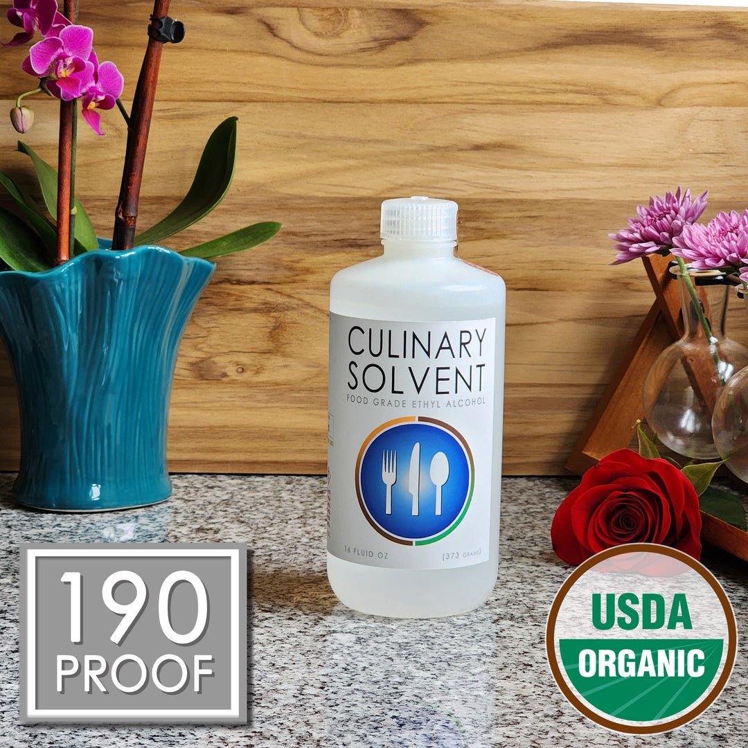 Pure Organic Perfumers Alcohol pint bottle by Culinary Solvent food grade ethanol with orchids, roses, and fresh flowers teak wood background